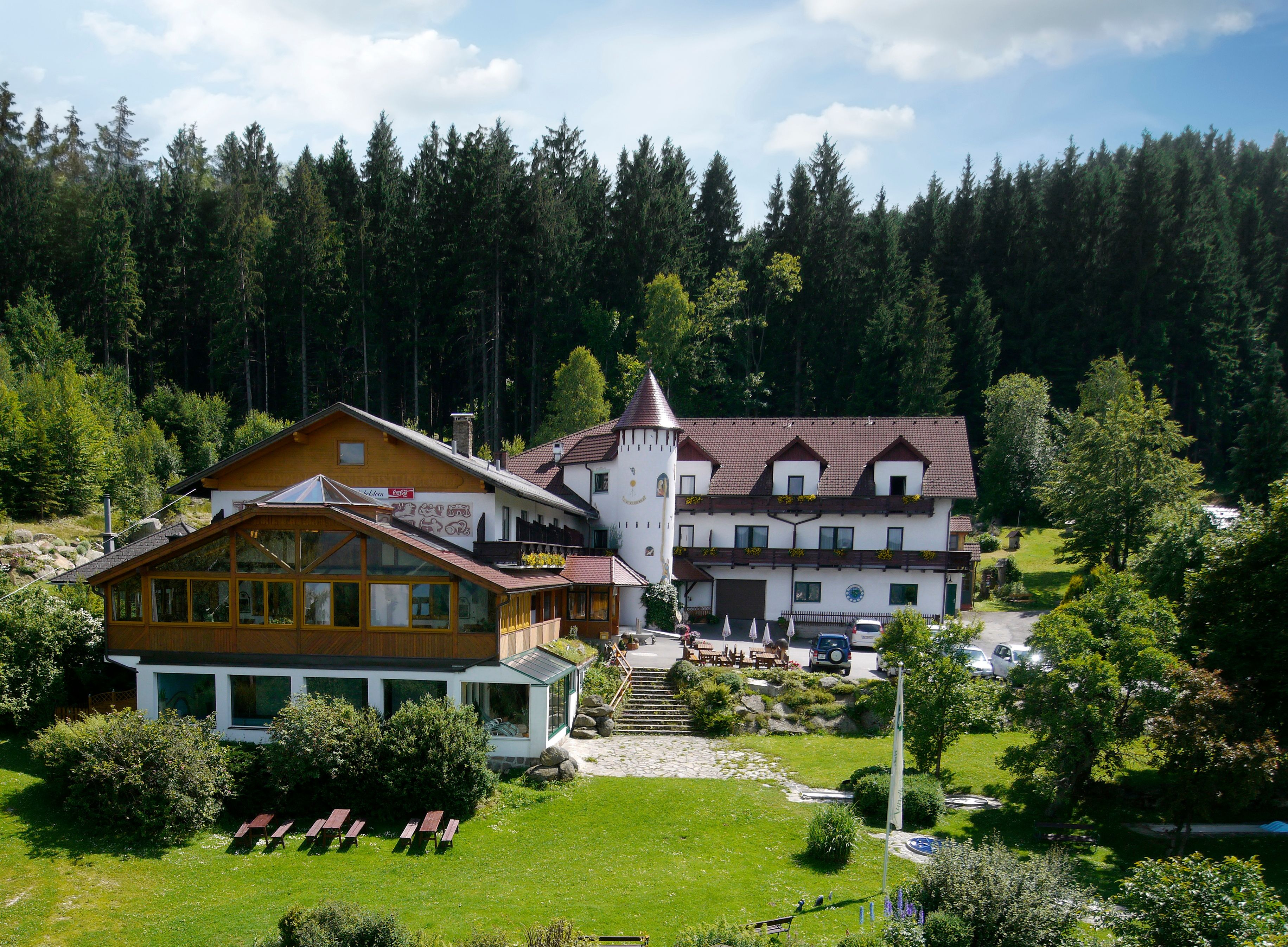 Hotel v lese s věží a zahradou.