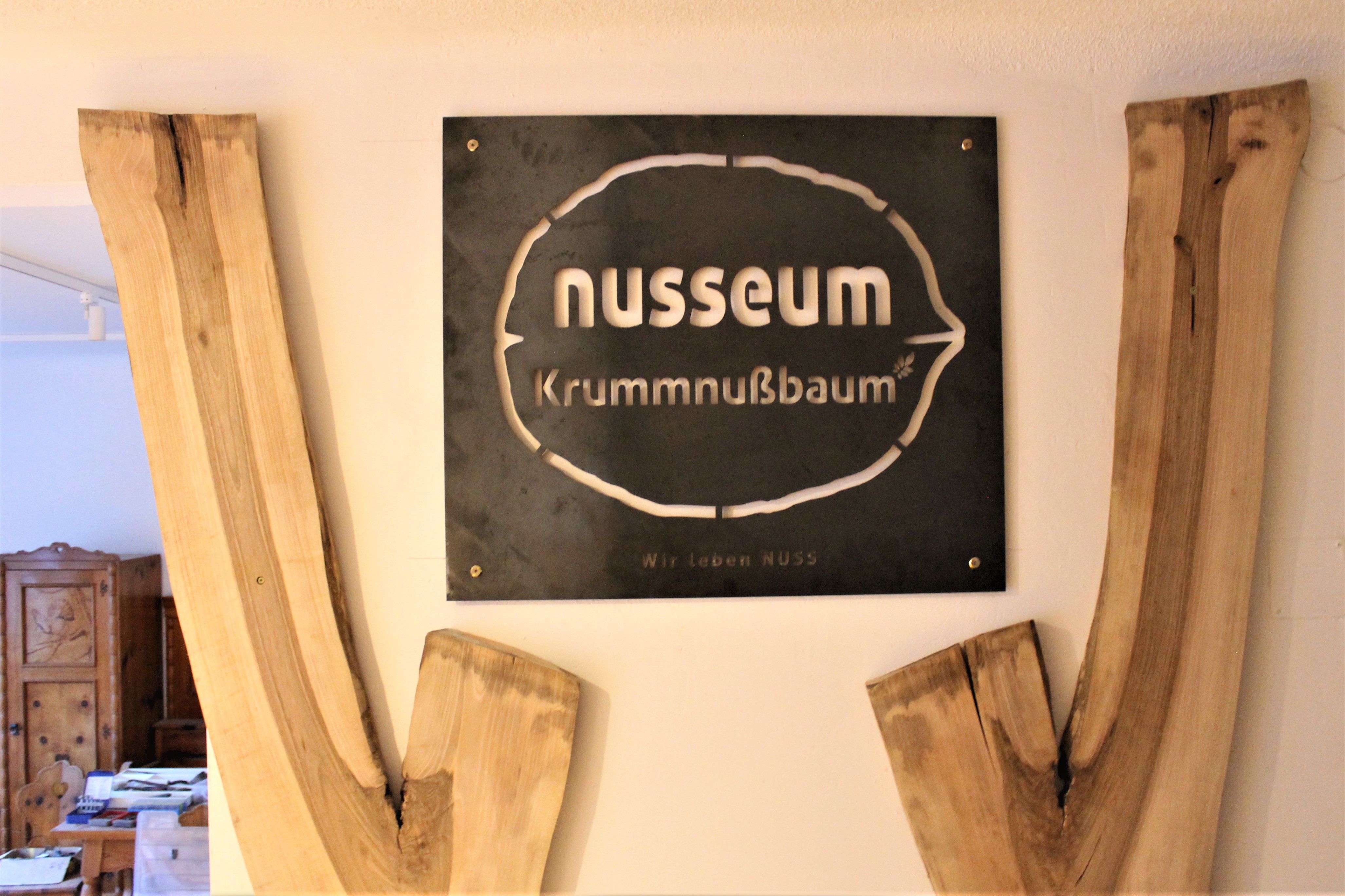 Znak Nusseum Krummnußbaum s dřevěnou výzdobou.