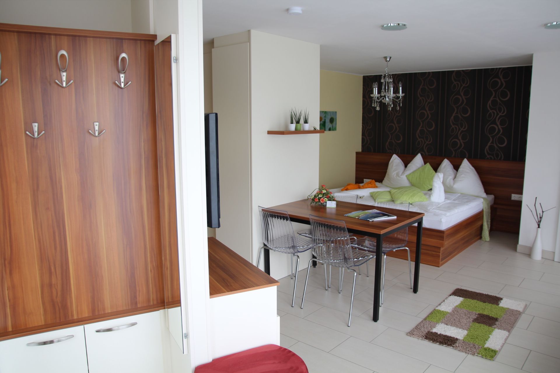 Moderní byt s dřevěným nábytkem, jídelním stolem, postelí a dekorativními prvky.