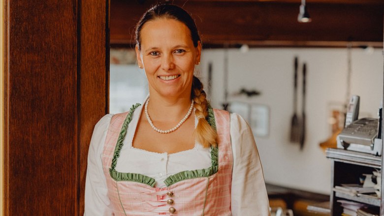 Žena v tradičním kroji se usmívá v restauraci.