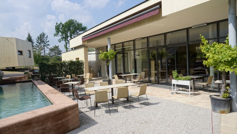Venkovn&iacute; prostor modern&iacute; sn&iacute;daňov&eacute; restaurace se stoly a židlemi na terase u vodn&iacute; n&aacute;drže.