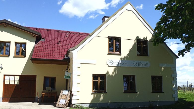 Žlutá budova s červenou střechou a nápisem "Rosenauer Stüberl".