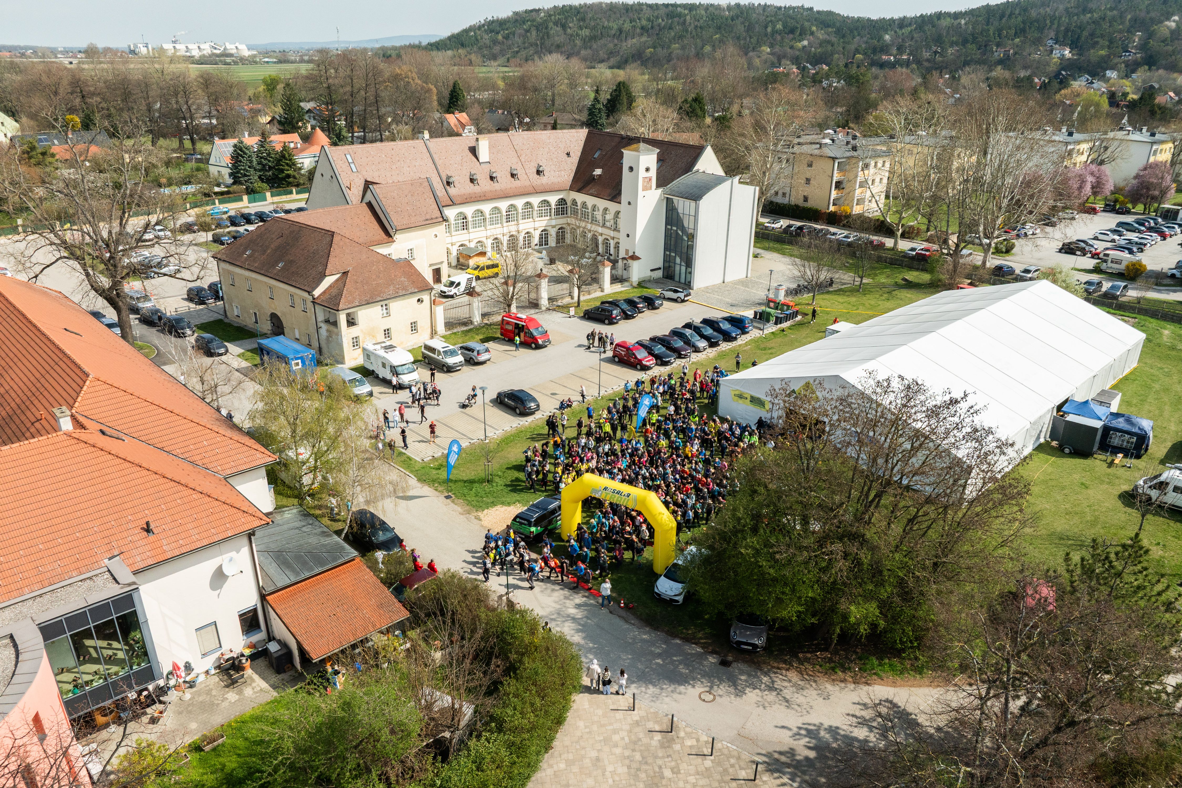 Letecký pohled na hrad s davem lidí, stany a budovami při soutěži Rosalia Trail Challenge.