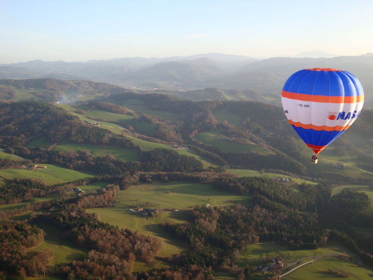 Horkovzdušný balón nad zelenou kopcovitou krajinou v Traisentalu.