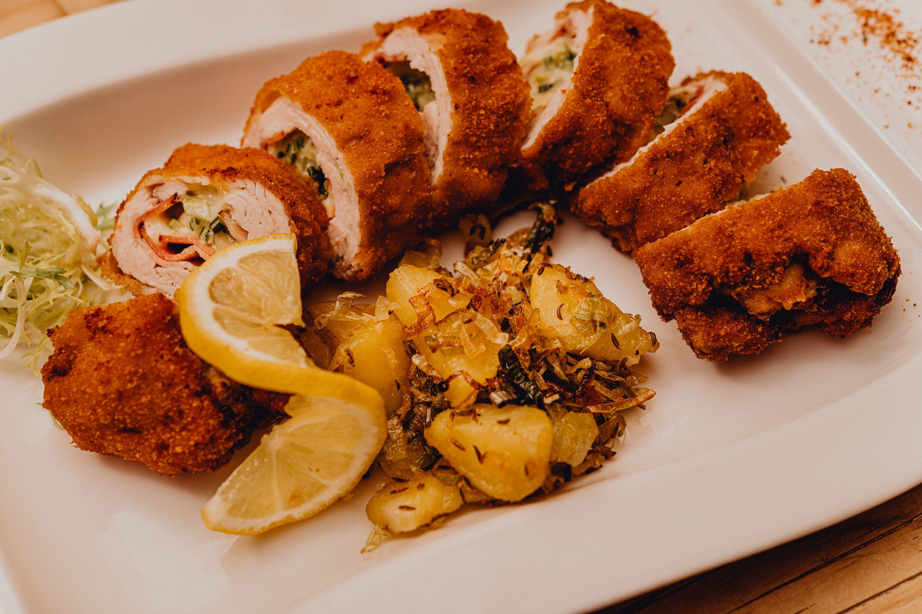 Plněné pečené krůtí filé s bramborovou přílohou a plátky citronu na bílém talíři.