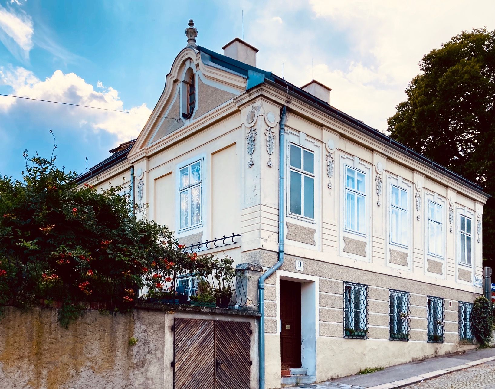 Vnější pohled na historickou vilu se zdobenými okny a štítem.