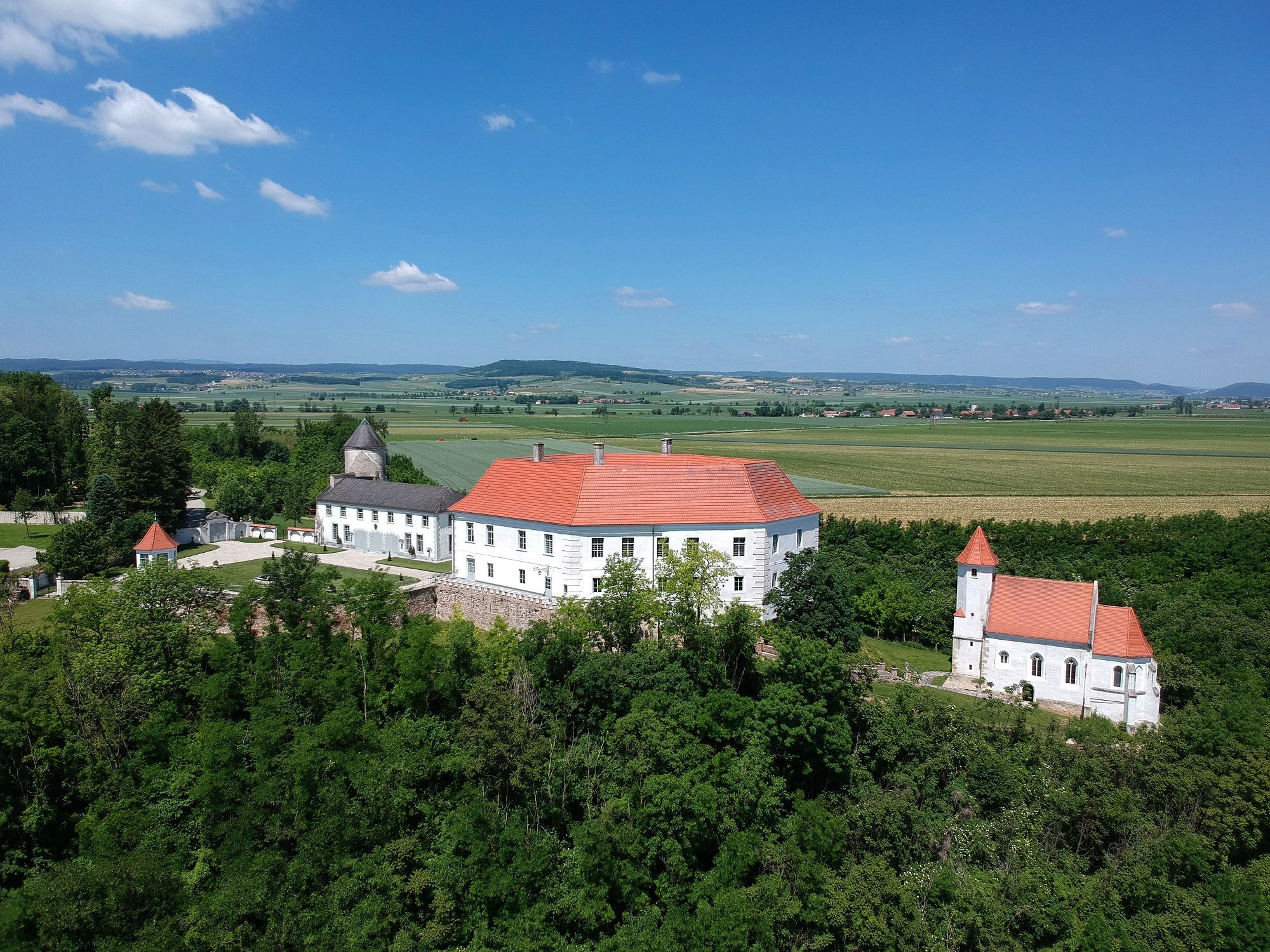Letecký pohled na hrad Viehofen s červenou střechou, obklopený zelenou krajinou a poli.