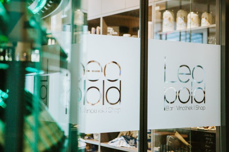 Vchod do vinotéky s nápisem "Leopold Bar Vinothek Shop" na skleněných dveřích.