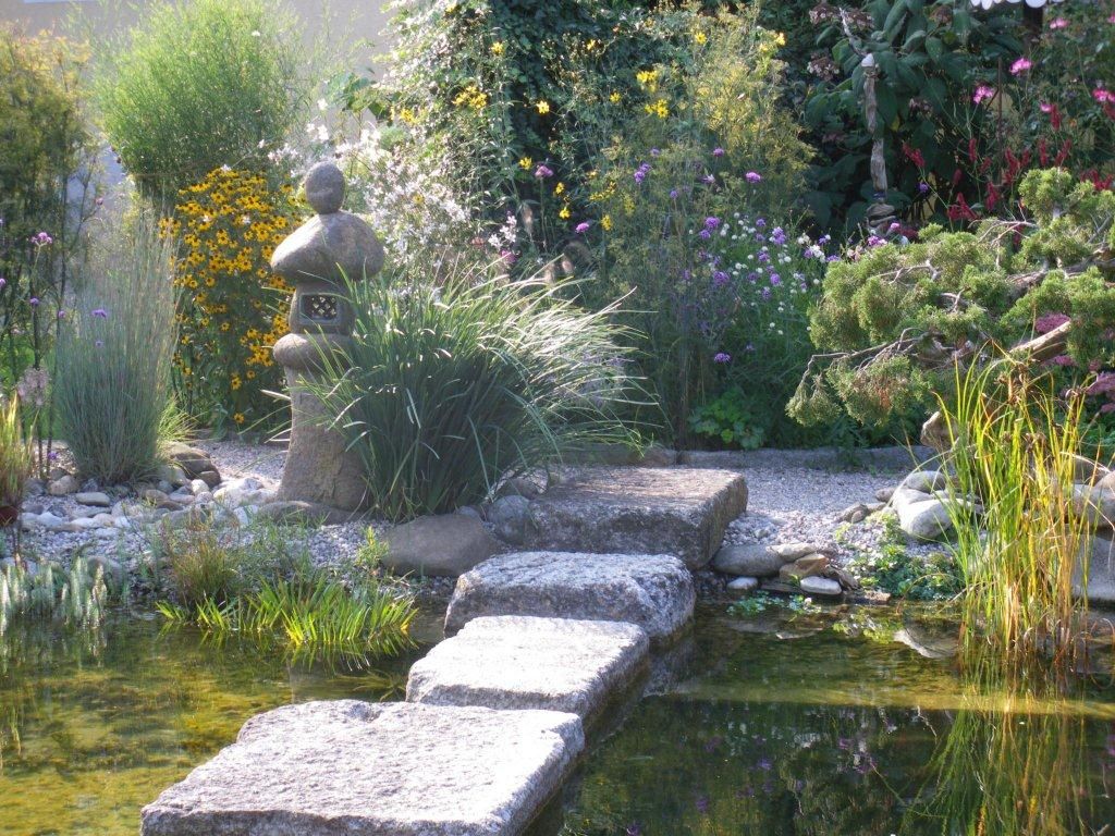 Ukázková zahrada s kamennou lucernou, květinami a jezírkem.