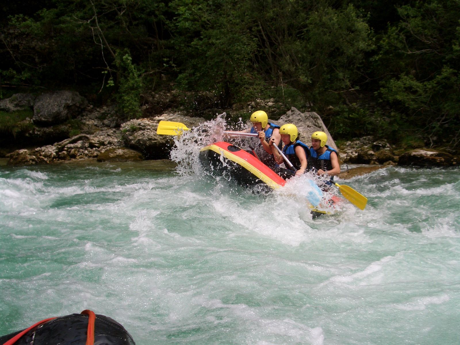 Skupina lidí na raftu na divoké řece.