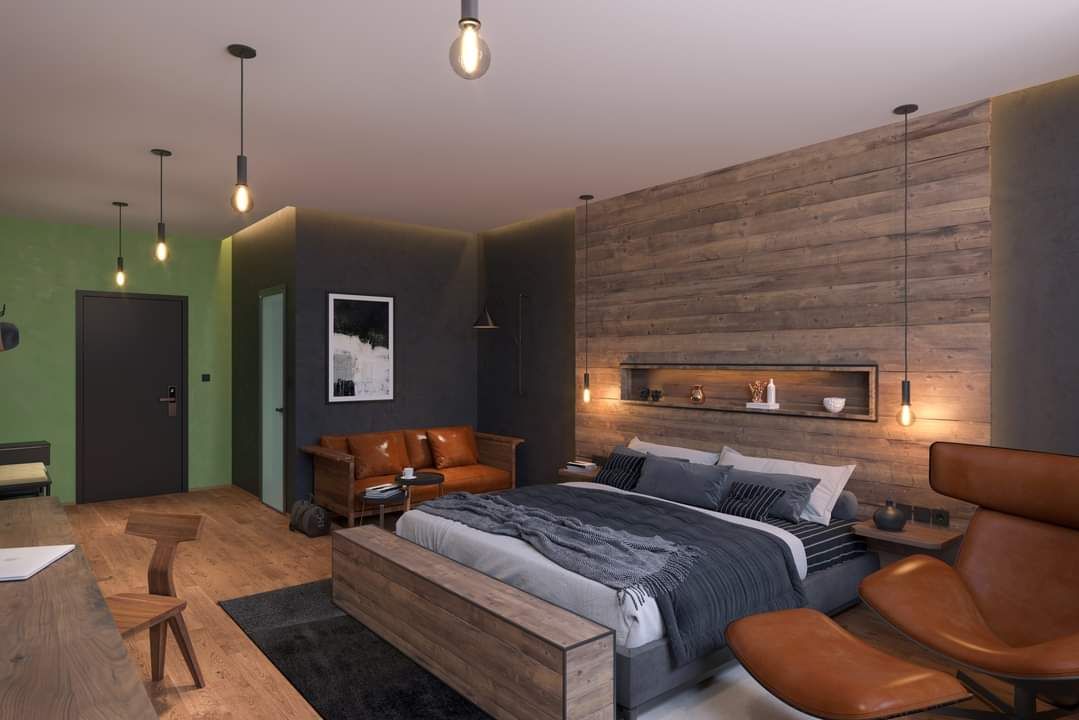 Moderní ložnice s dřevěnou stěnou, velkou postelí, koženou pohovkou a stylovými lampami.