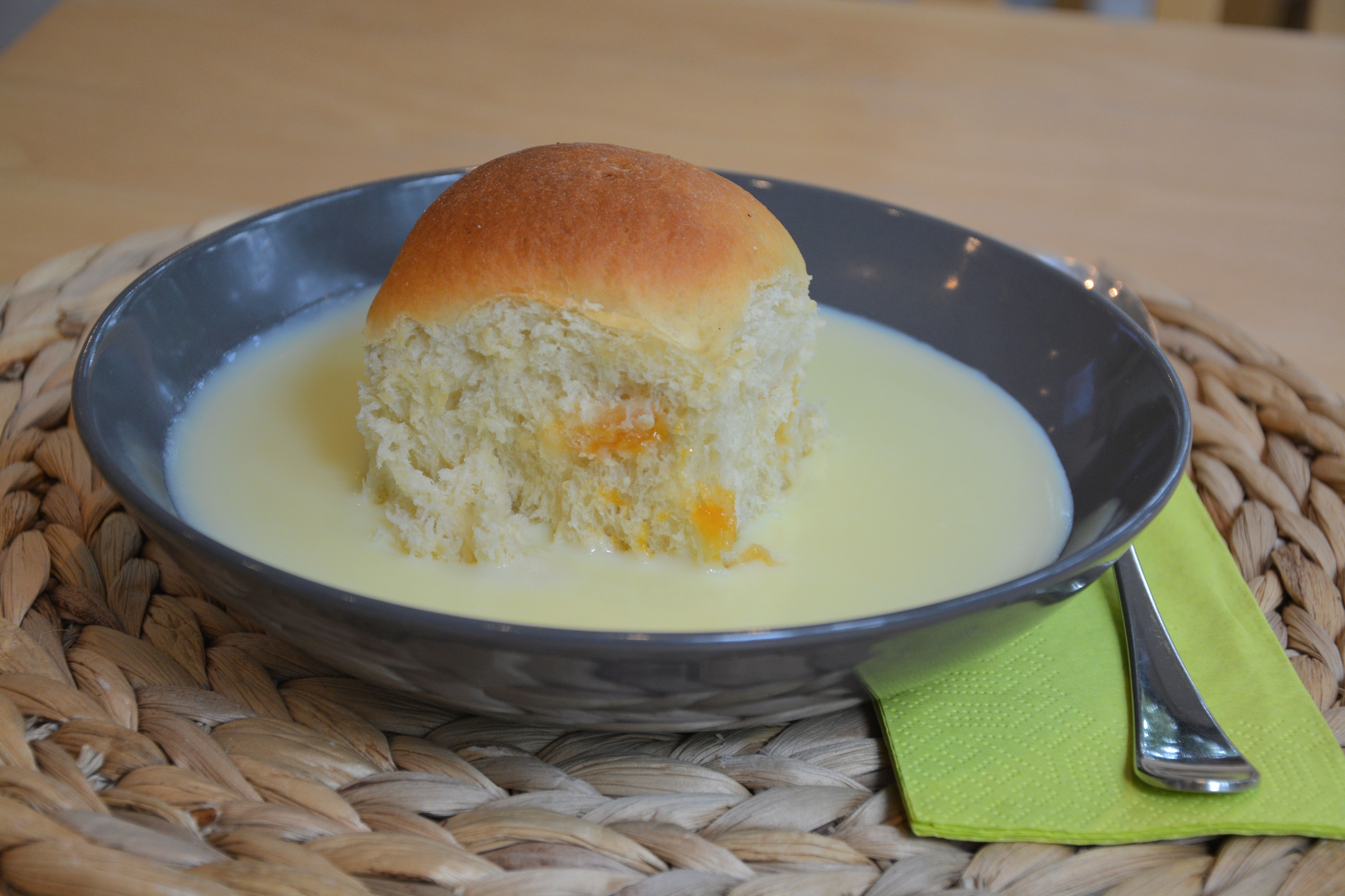 Černý talíř s dortem a vanilkovou omáčkou, vedle zelený ubrousek s vidličkou.