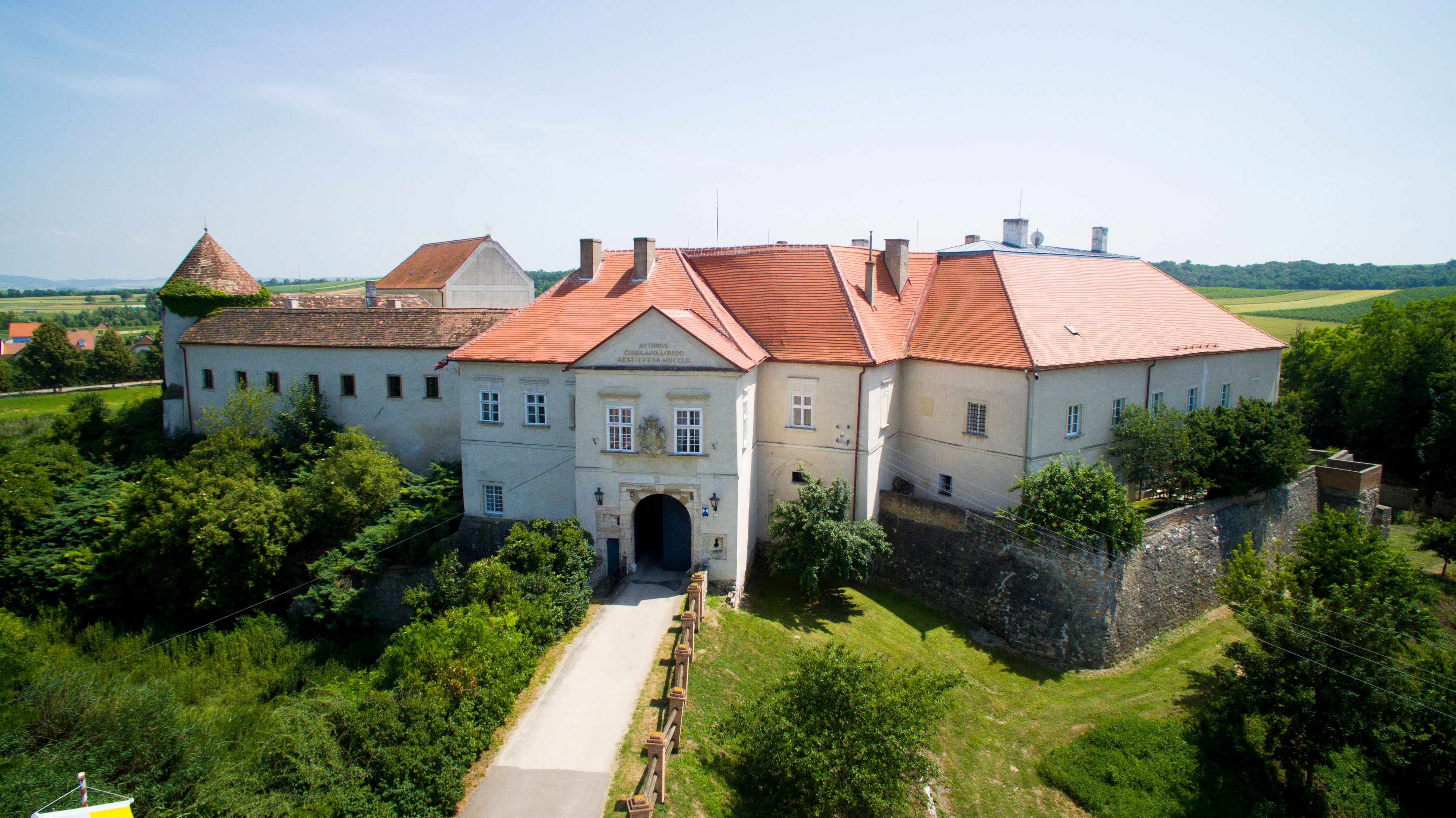 Letecký pohled na hrad Mailberg s červenými střechami a okolní krajinu.