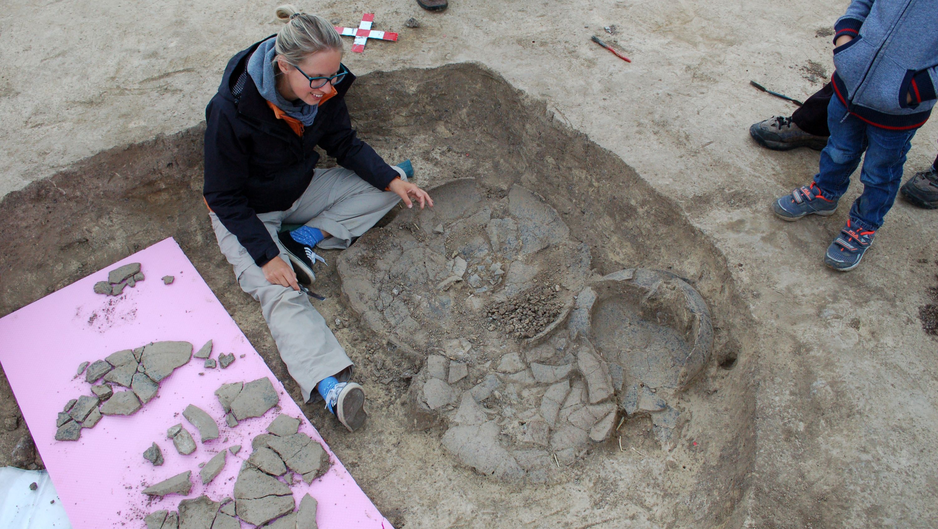 Archeolog zkoumá rozbitou keramiku na vykopávkách.