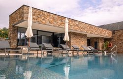 Pohled zvenčí na moderní hotel s bazénem a lehátky.