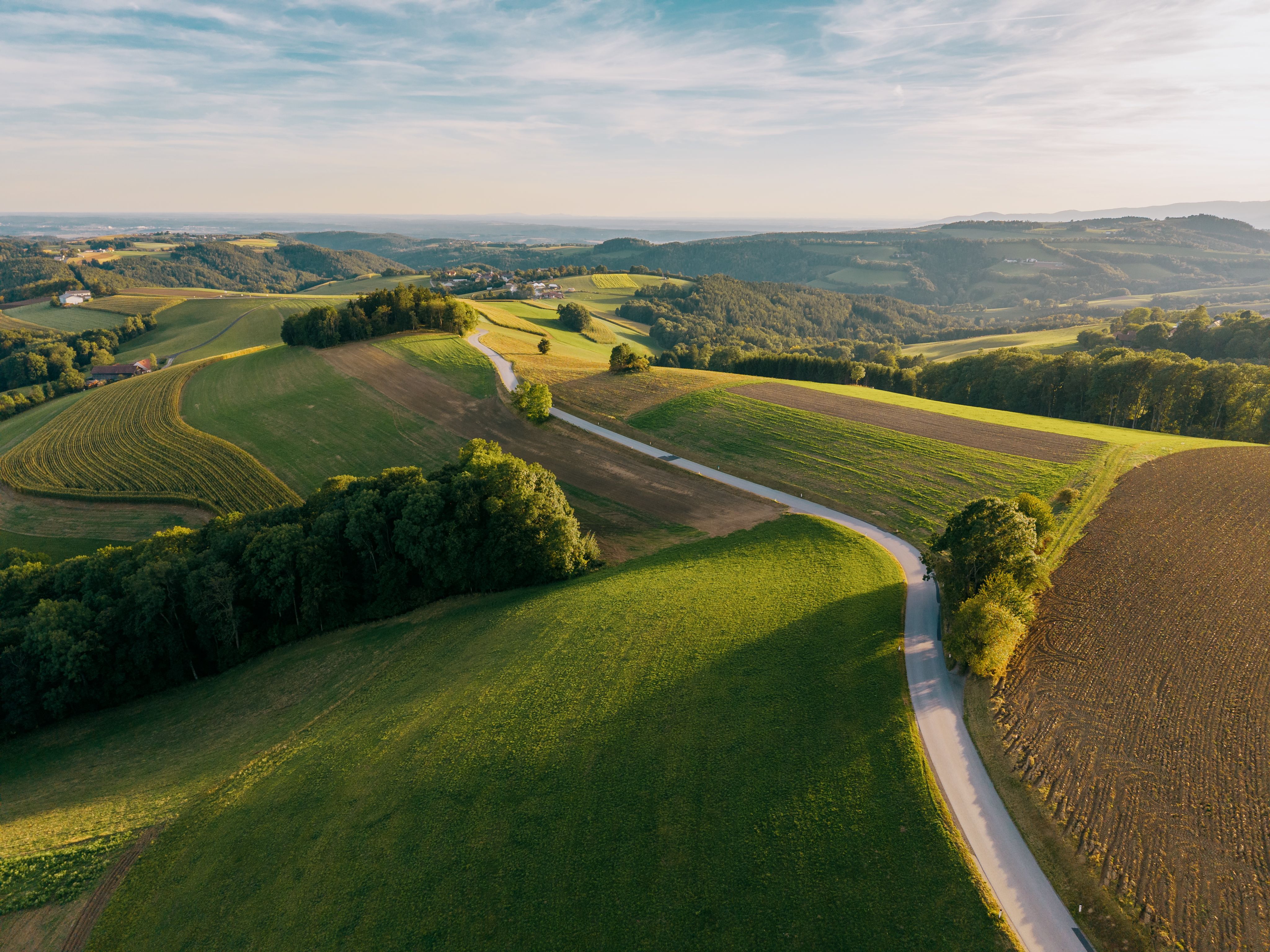 Letecký pohled na kopcovitou krajinu s poli a lesy v Hattmannsdorfu, Hochneukirchen.