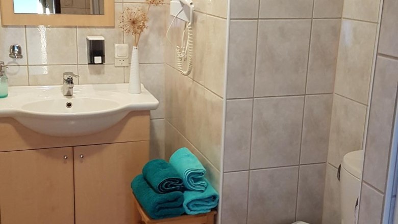 Koupelna s umyvadlem, zrcadlem, toaletou a ručn&iacute;ky na stoličce.