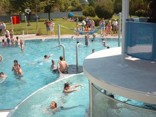 Koupání a hry probíhají ve venkovním bazénu se skluzavkou a zelení.