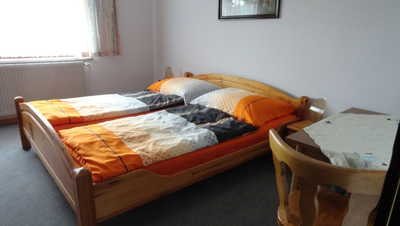 Jednodu&scaron;e zař&iacute;zen&aacute; ložnice se dvěma samostatn&yacute;mi lůžky, stolem a židl&iacute;.