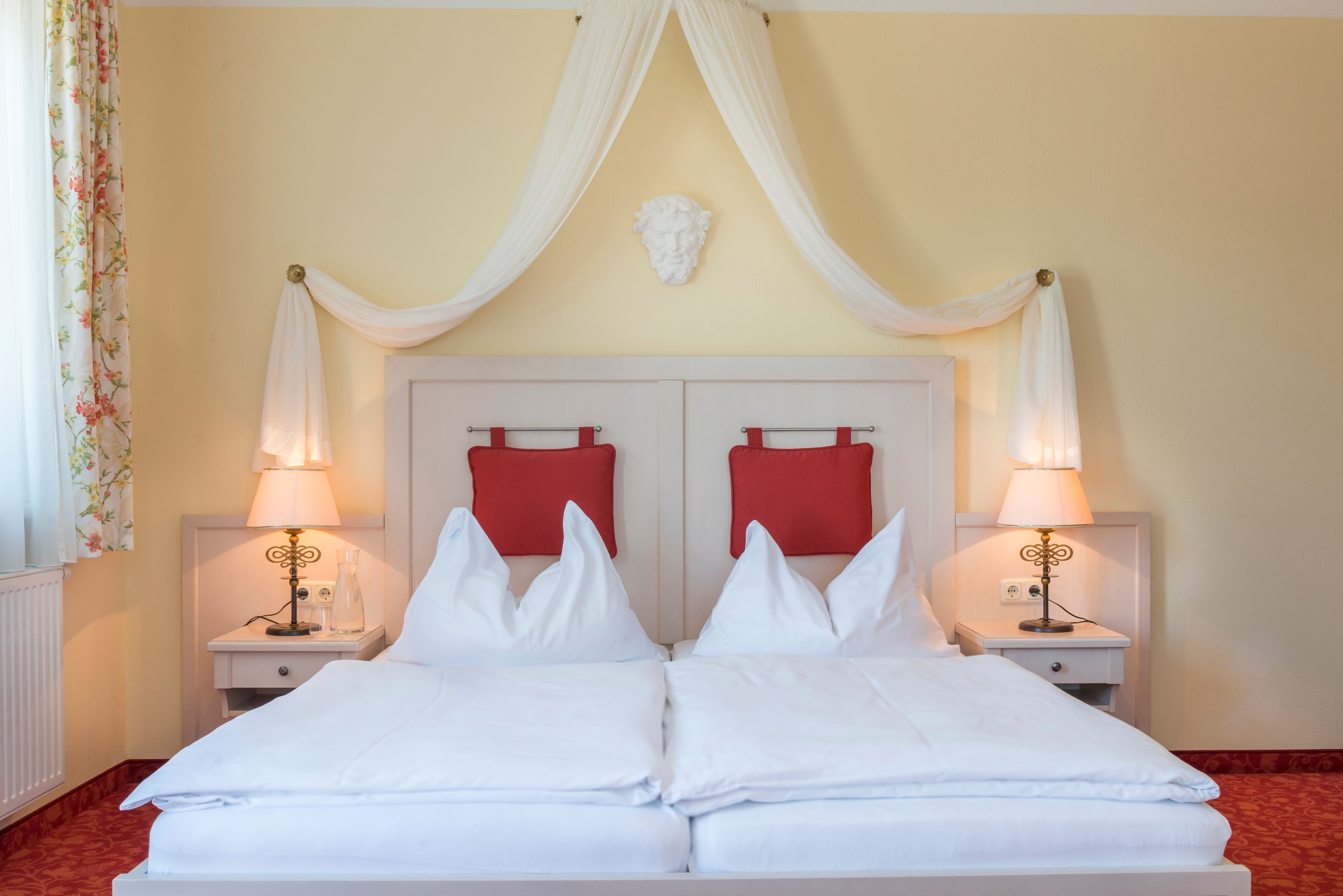 Pohled na pokoj s postelí s nebesy a červeným čalouněním