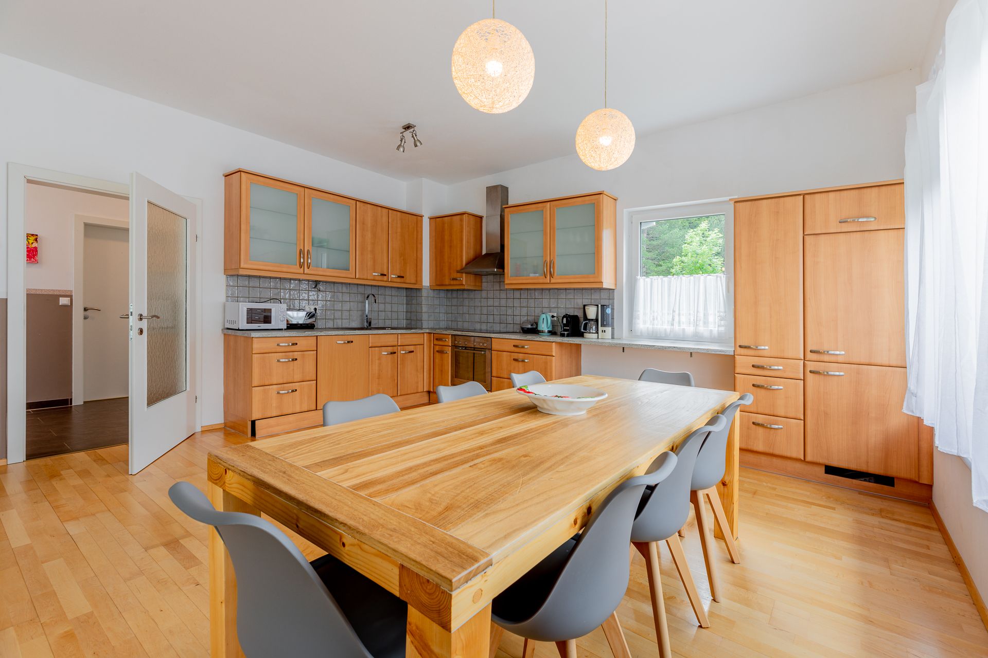 Moderní kuchyně s dřevěným nábytkem a velkým jídelním stolem.
