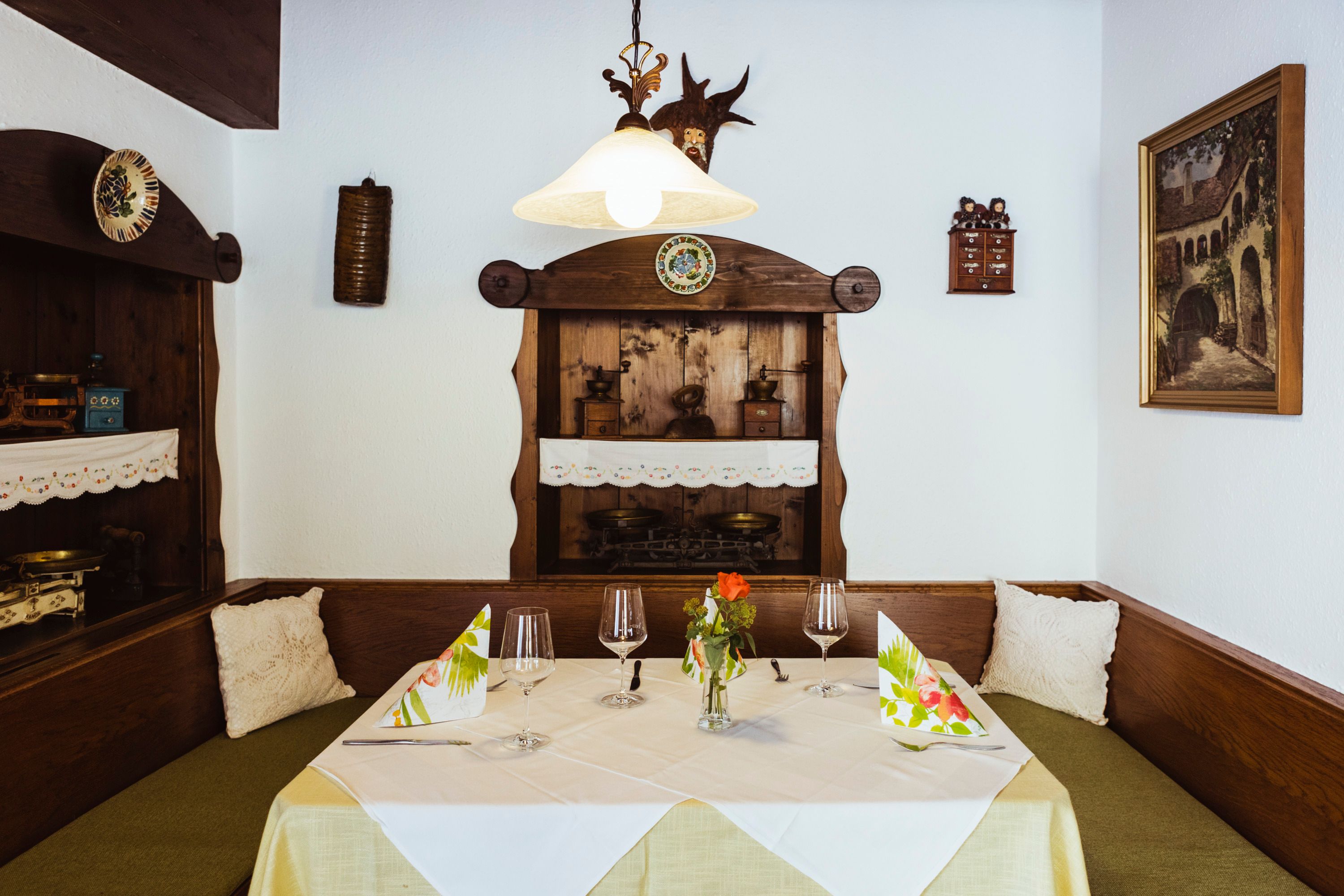 Útulné posezení v restauraci s dřevěným nábytkem, dekorativními detaily a prostíráním.