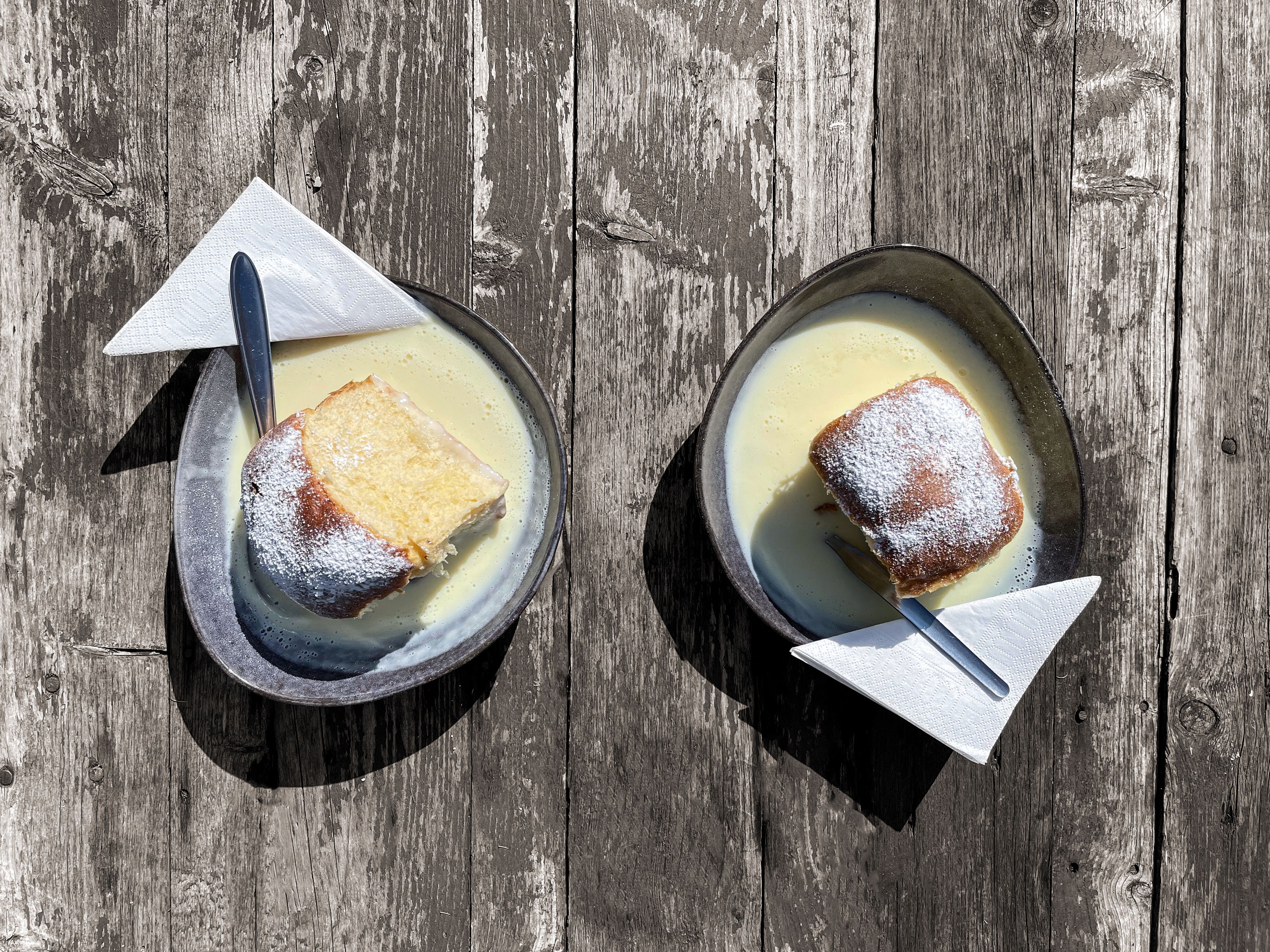 Lidé na nádraží s vlakem a dřevěnou budovou.