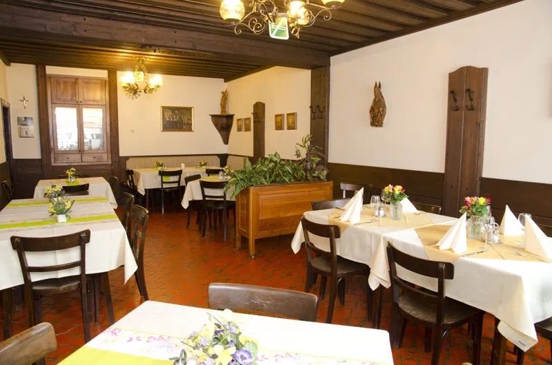 Pohled do interiéru tradiční restaurace s dřevěným nábytkem a zdobenými stoly.