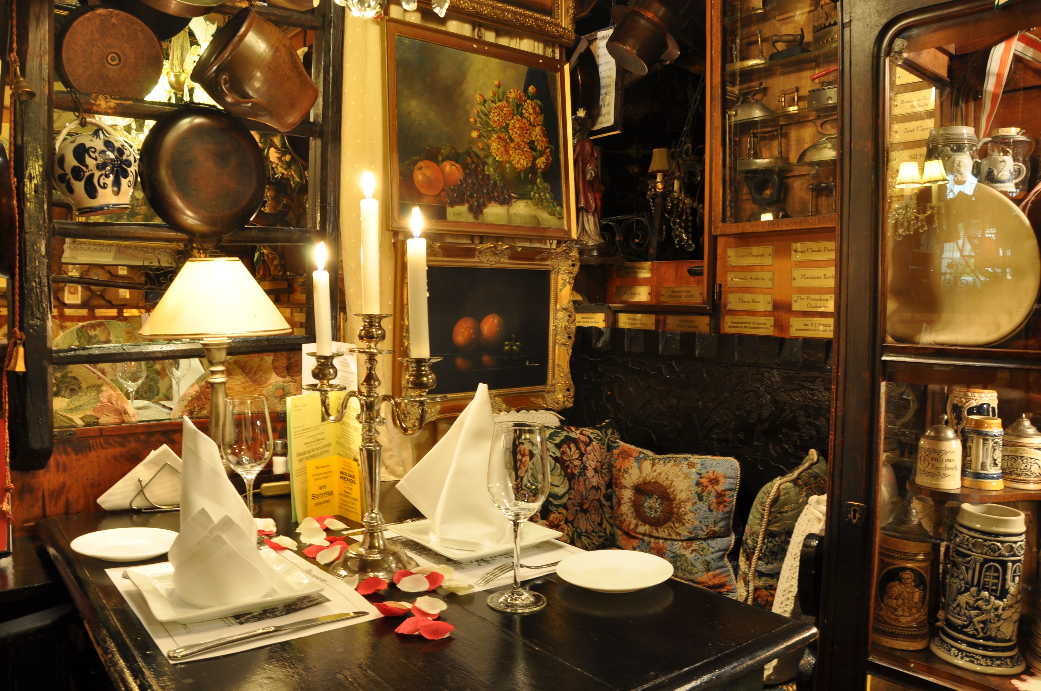 Útulně vyzdobený stůl v rustikální restauraci se svícny, obrazy a starožitnými předměty.