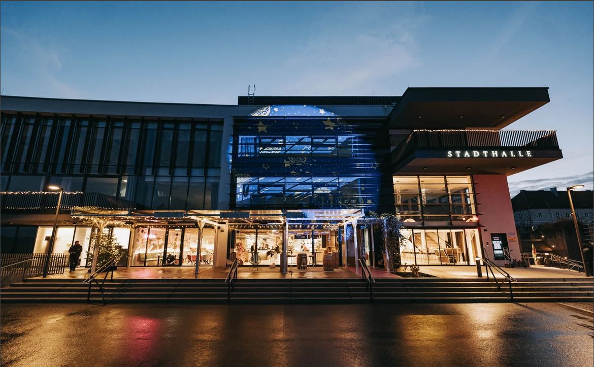 Vnější pohled na Stadthalle Ybbs za soumraku s osvětleným vchodem.