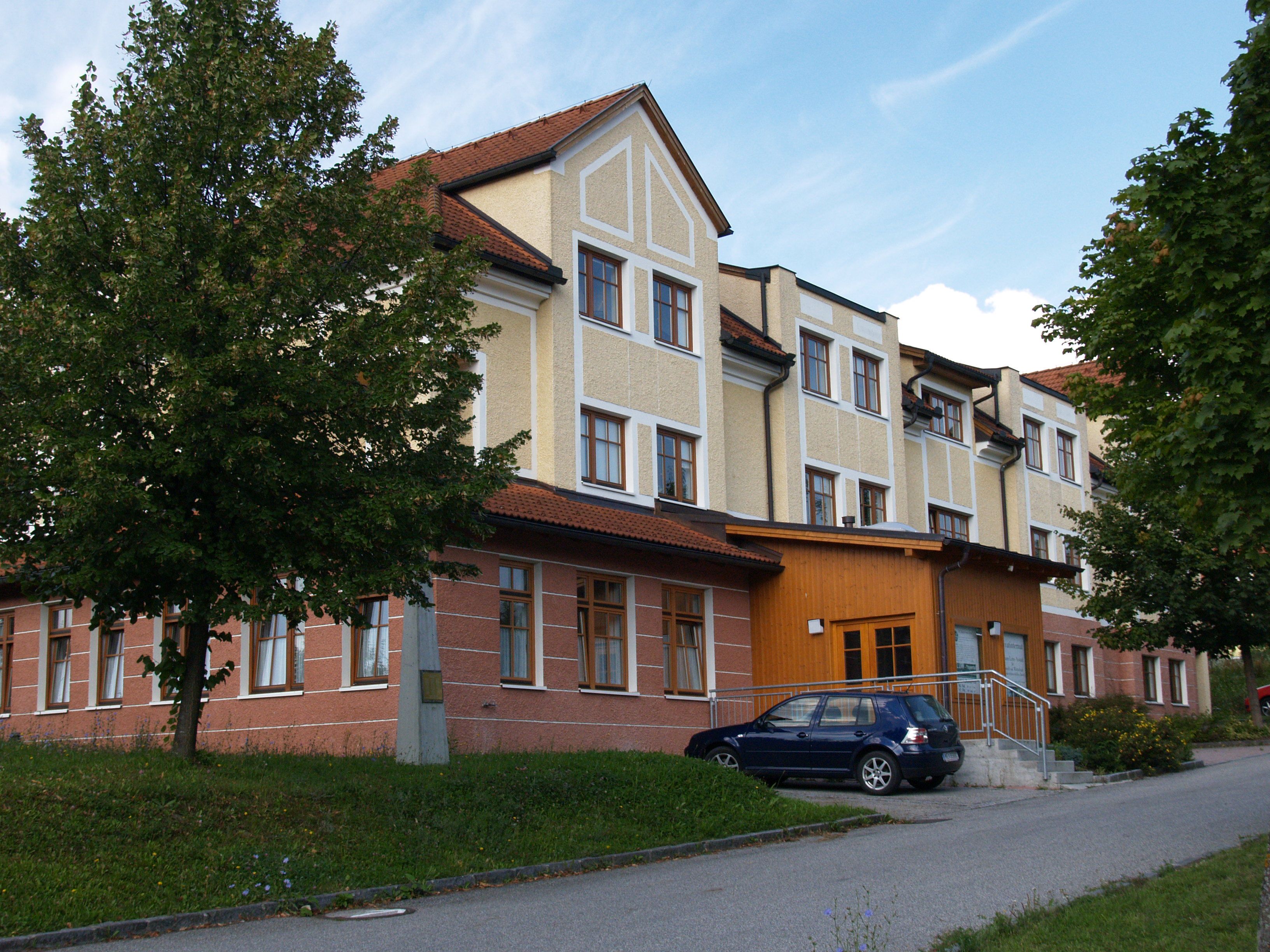 Penzion HLUW-Yspertal se zaparkovaným autem a stromy.