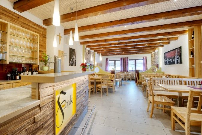 Pohled do interiéru útulné jídelny s dřevěným nábytkem a barem ve stylu vinárny.