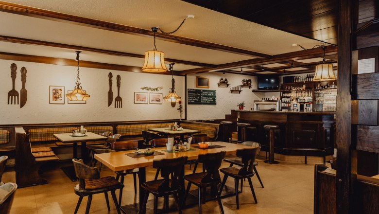 &Uacute;tuln&aacute; hospůdka s dřevěn&yacute;m n&aacute;bytkem, barem a dekorativn&iacute;mi lampami.