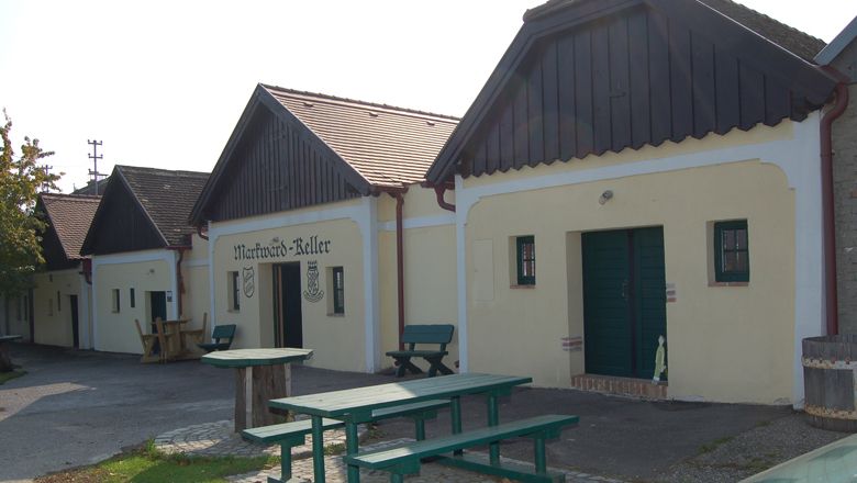 Tradiční vinné sklepy s dřevěnými lavicemi a venkovními stoly.