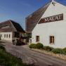 Vnější pohled na vinařství a hotel MALAT s moderní architekturou a vozidlem v popředí.