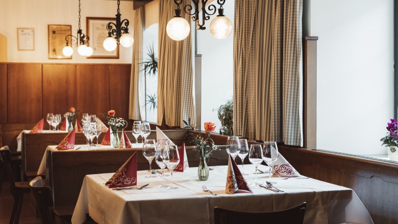 Útulná restaurace s prostřenými stoly, sklenicemi na víno a vázami na květiny.