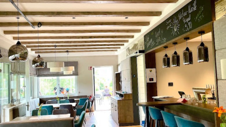 Restaurace uvnitř se stoly a zelen&yacute;mi křesly