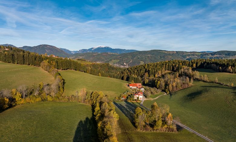 Krajina u St. Corona am Wechsel se zelenými kopci a statkem.