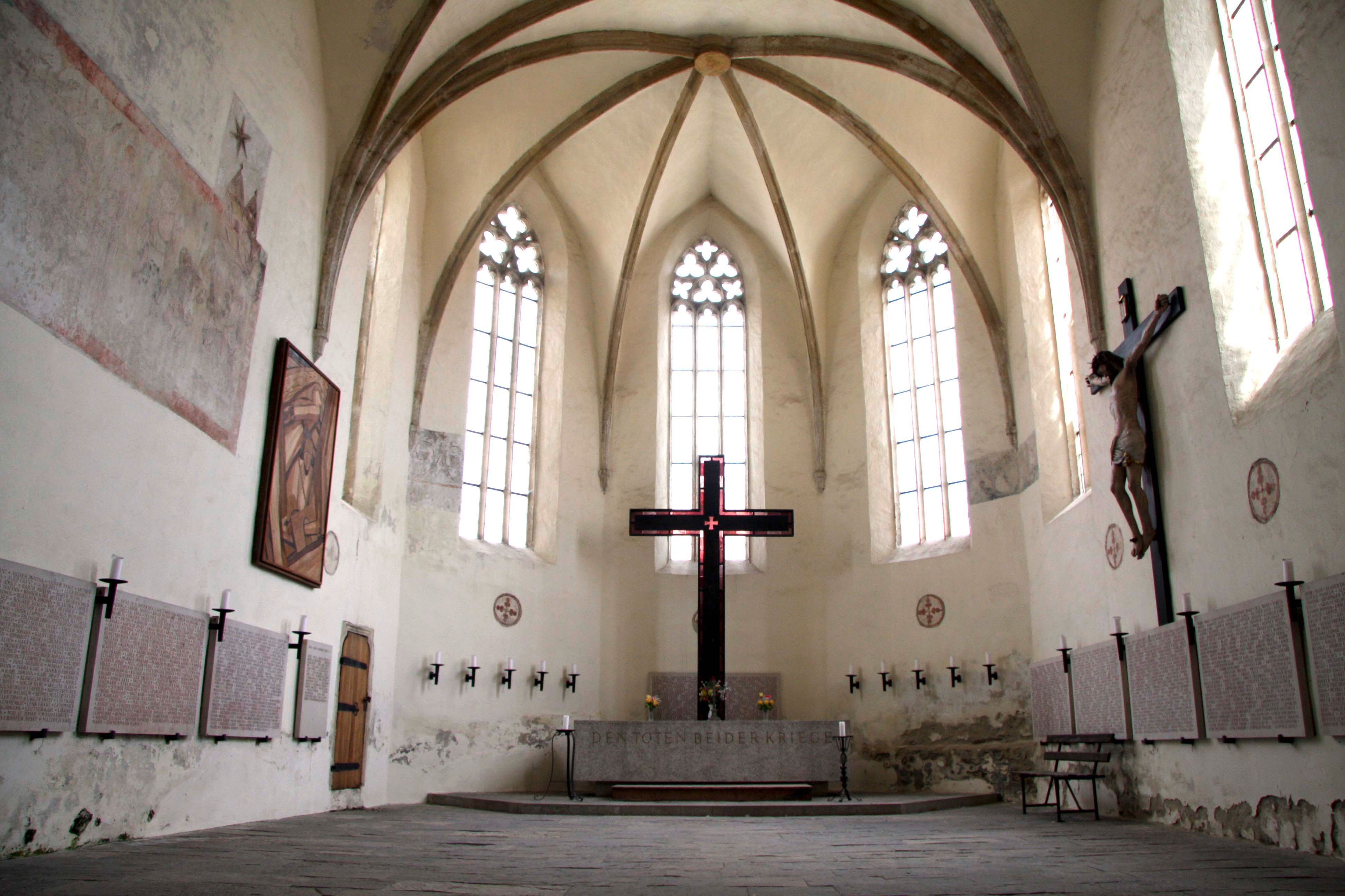 Pohled do interiéru kostela Frauenbergkirche Stein s gotickými okny a velkým křížem.