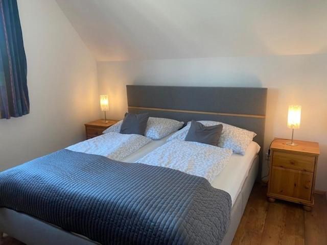 Útulná ložnice s manželskou postelí, dvěma nočními stolky a lampičkami.