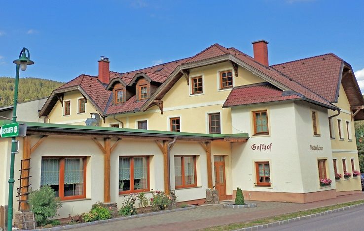 Tradiční hostinec se žlutou fasádou a červenými střechami.