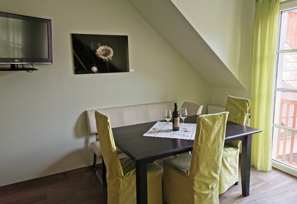 Jídelní kout v rekreačním bytě se stolem, židlemi a lahví vína.