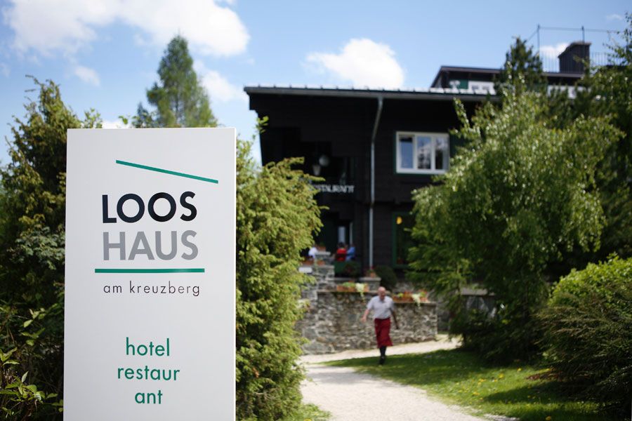 Vchod do Looshaus am Kreuzberg s nápisem a zahradou.