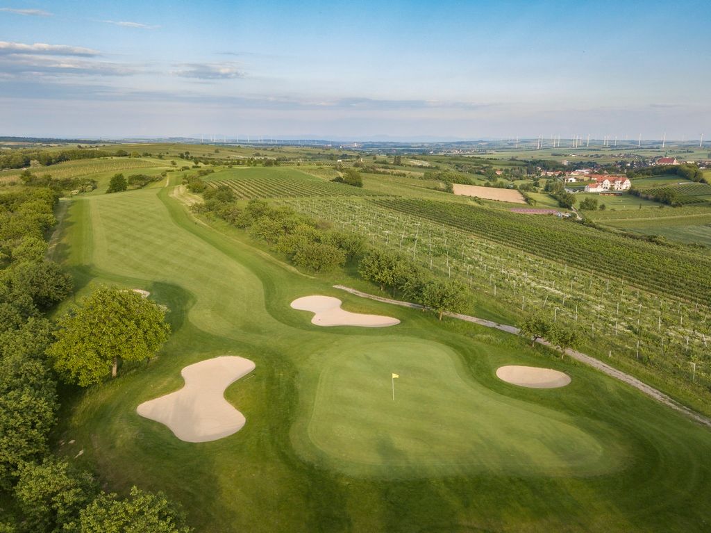 Letecký pohled na golfové hřiště s písečnými bunkry a okolními vinicemi.