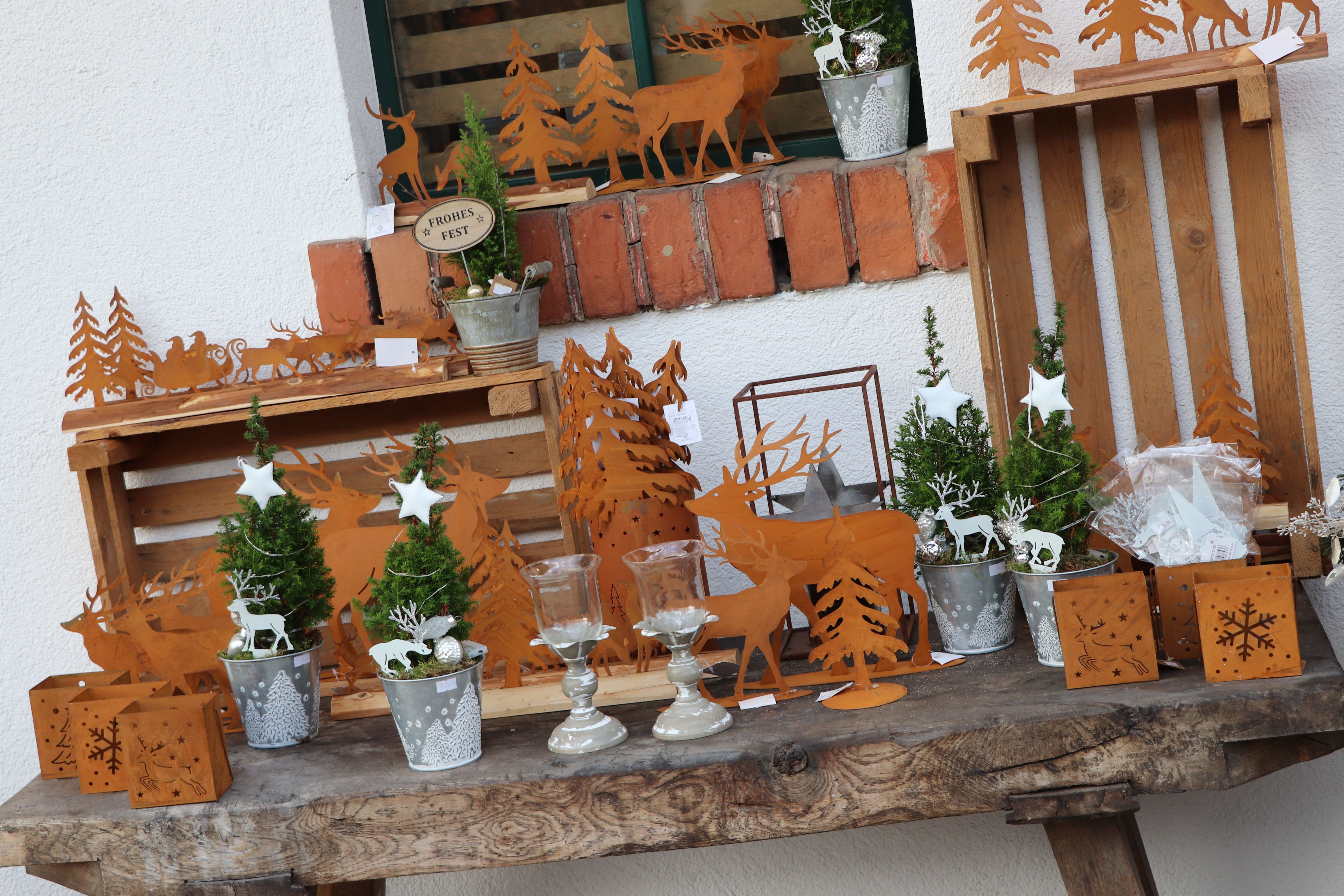 Vánoční dekorace s kovovými motivy sobů a vánočního stromku na dřevěném stole.