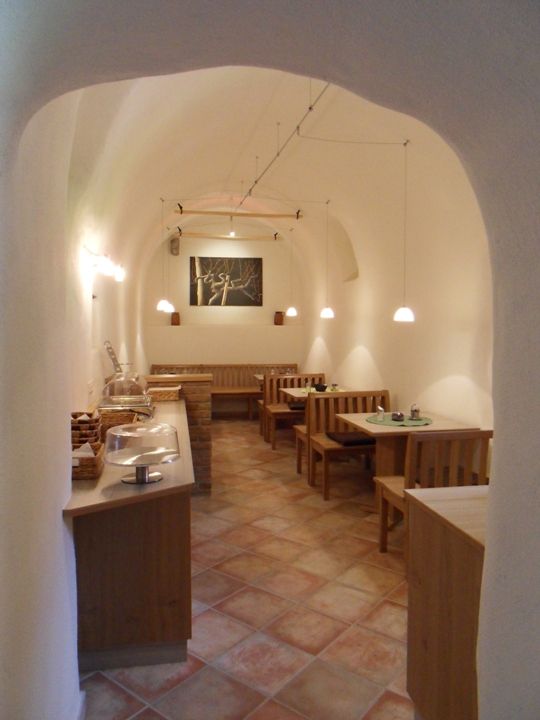 Útulná snídaňová místnost s dřevěným nábytkem a klenutým stropem.