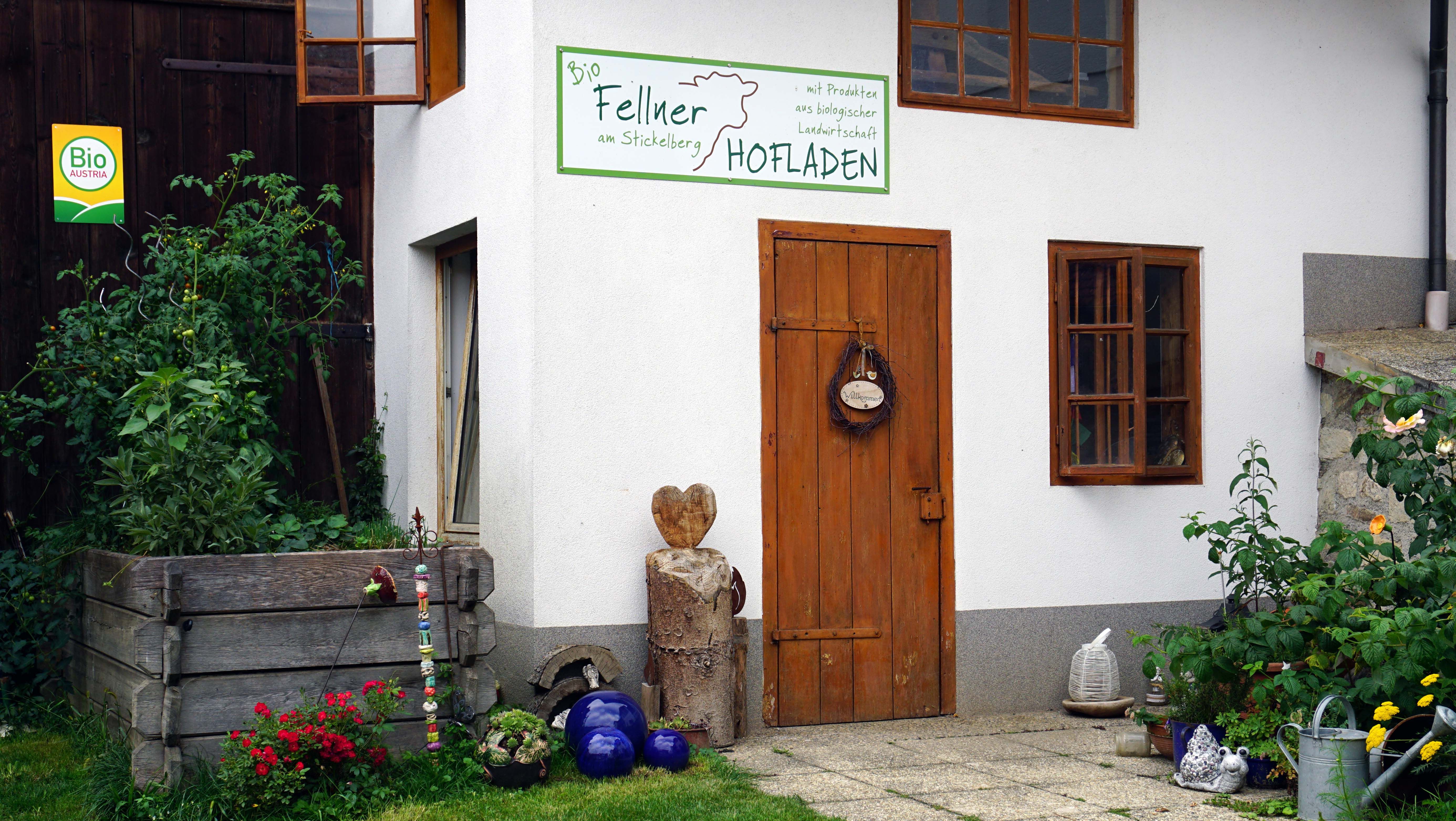 Farmářský obchod z ekologické farmy na Stickelbergu s dřevěnými dveřmi a rostlinami.