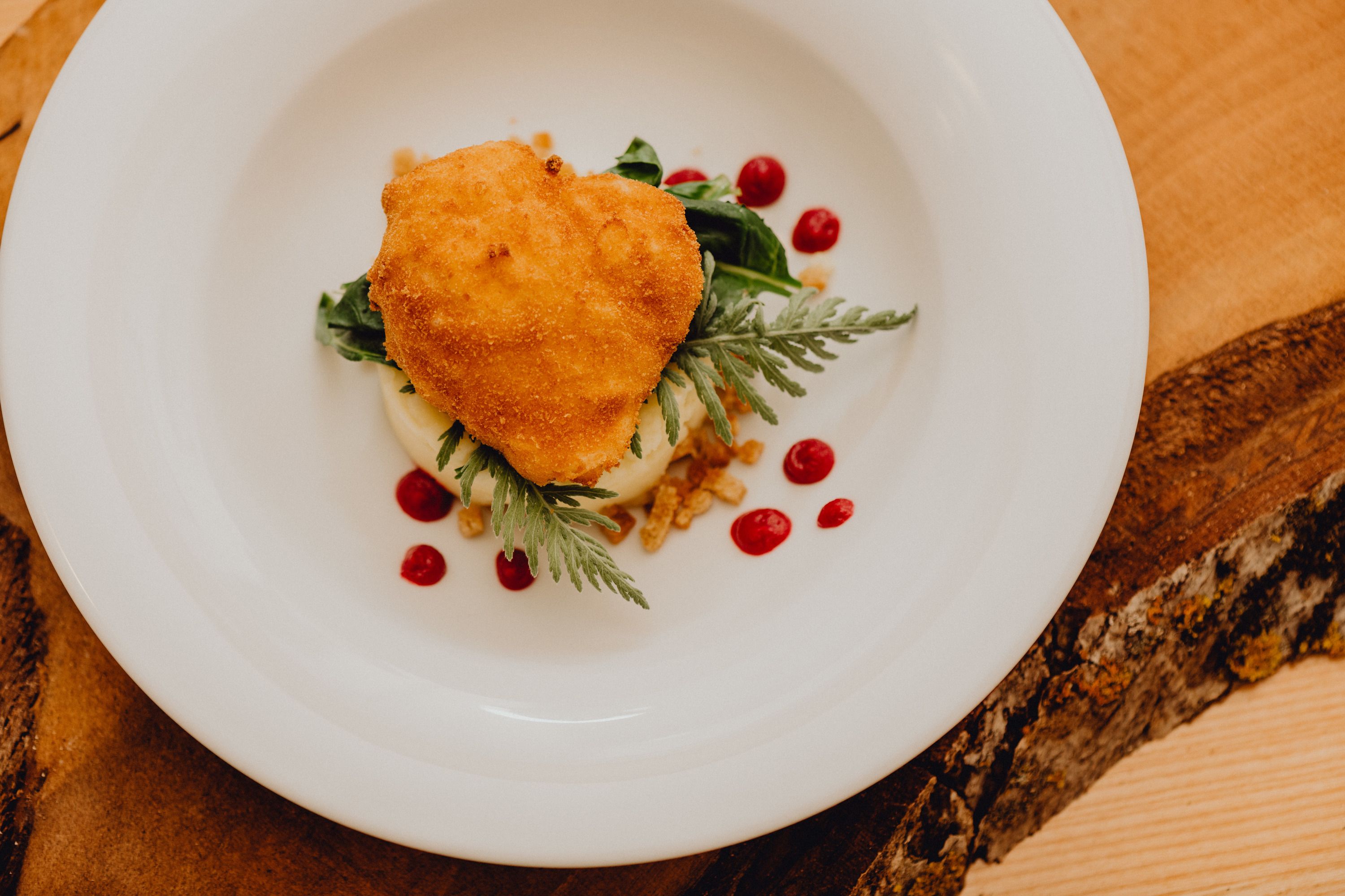 Pečené vejce na talíři s pyré a červenými puntíky.