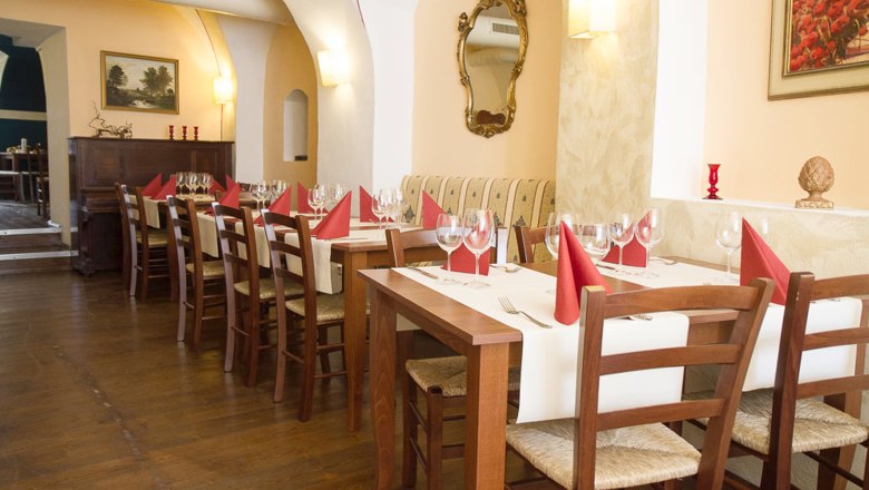 Elegantn&iacute; restaurace s prostřen&yacute;mi stoly a červen&yacute;mi ubrousky.