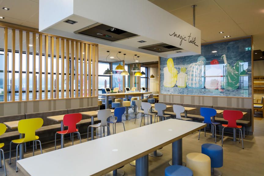 Pohled do interiéru moderní restaurace McDonald's s barevnými židlemi a stoly.